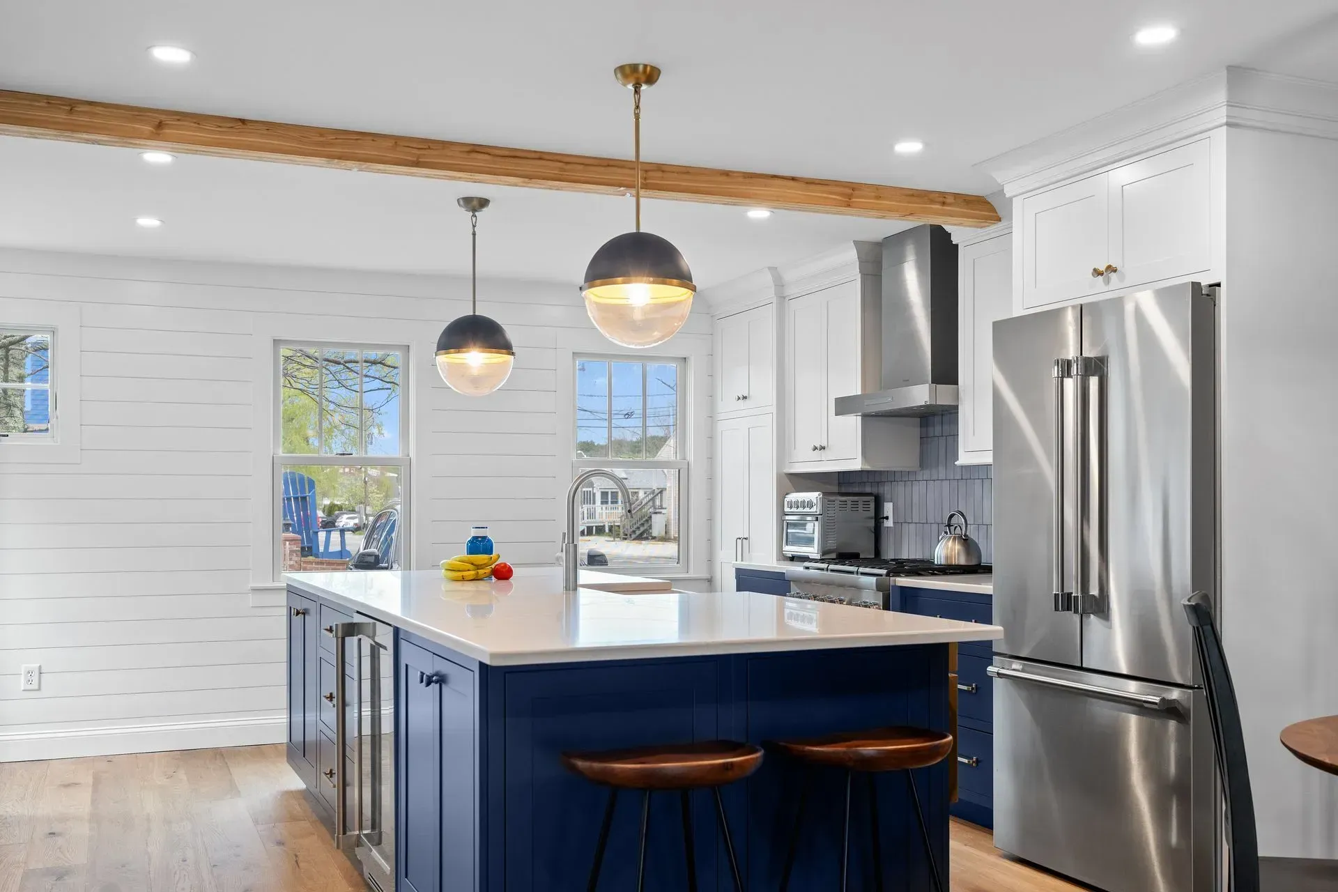 Bright modern kitchen with navy island, stainless steel appliances, and pendant lights