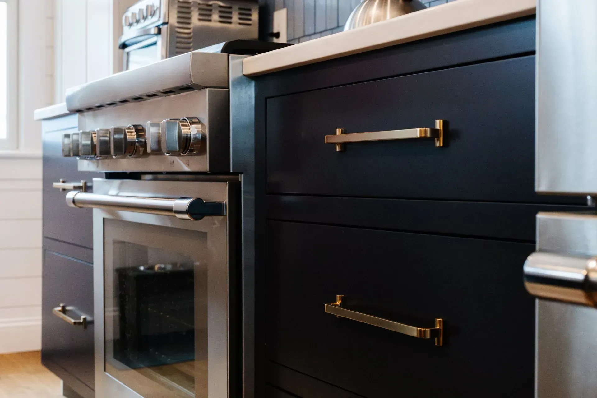 Modern kitchen with stainless steel oven and dark cabinets with brass handles