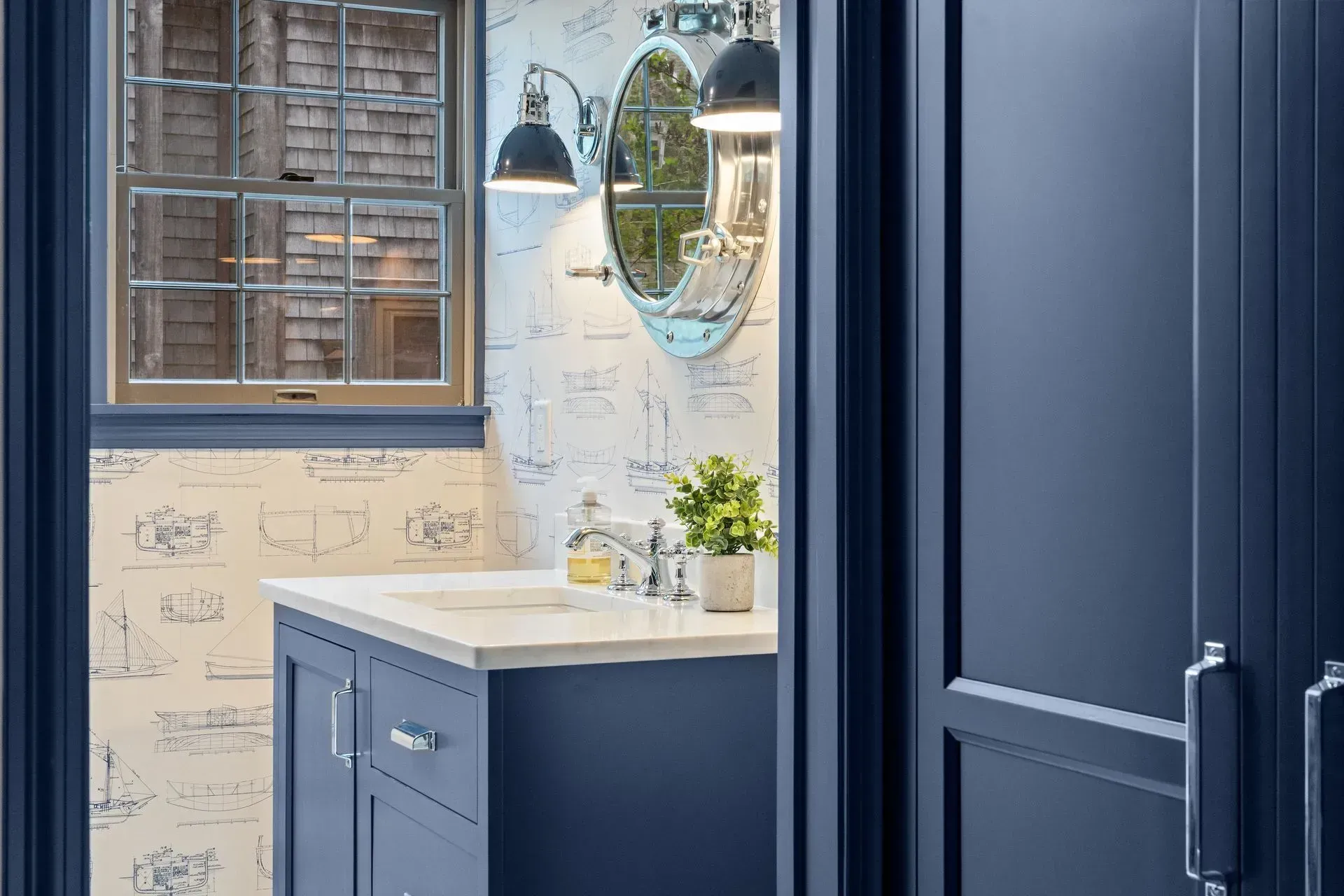 Blue bathroom vanity with sink, mirror, and window in a bright tiled room
