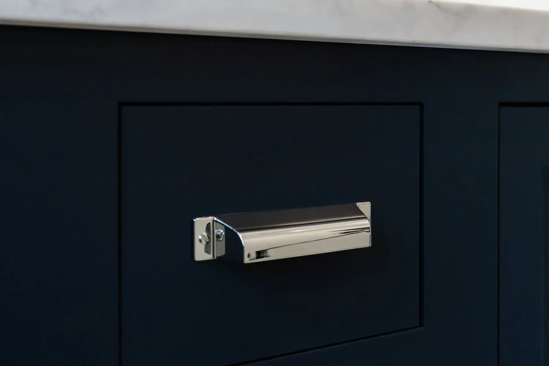 Silver mailbox slot on a dark blue door panel