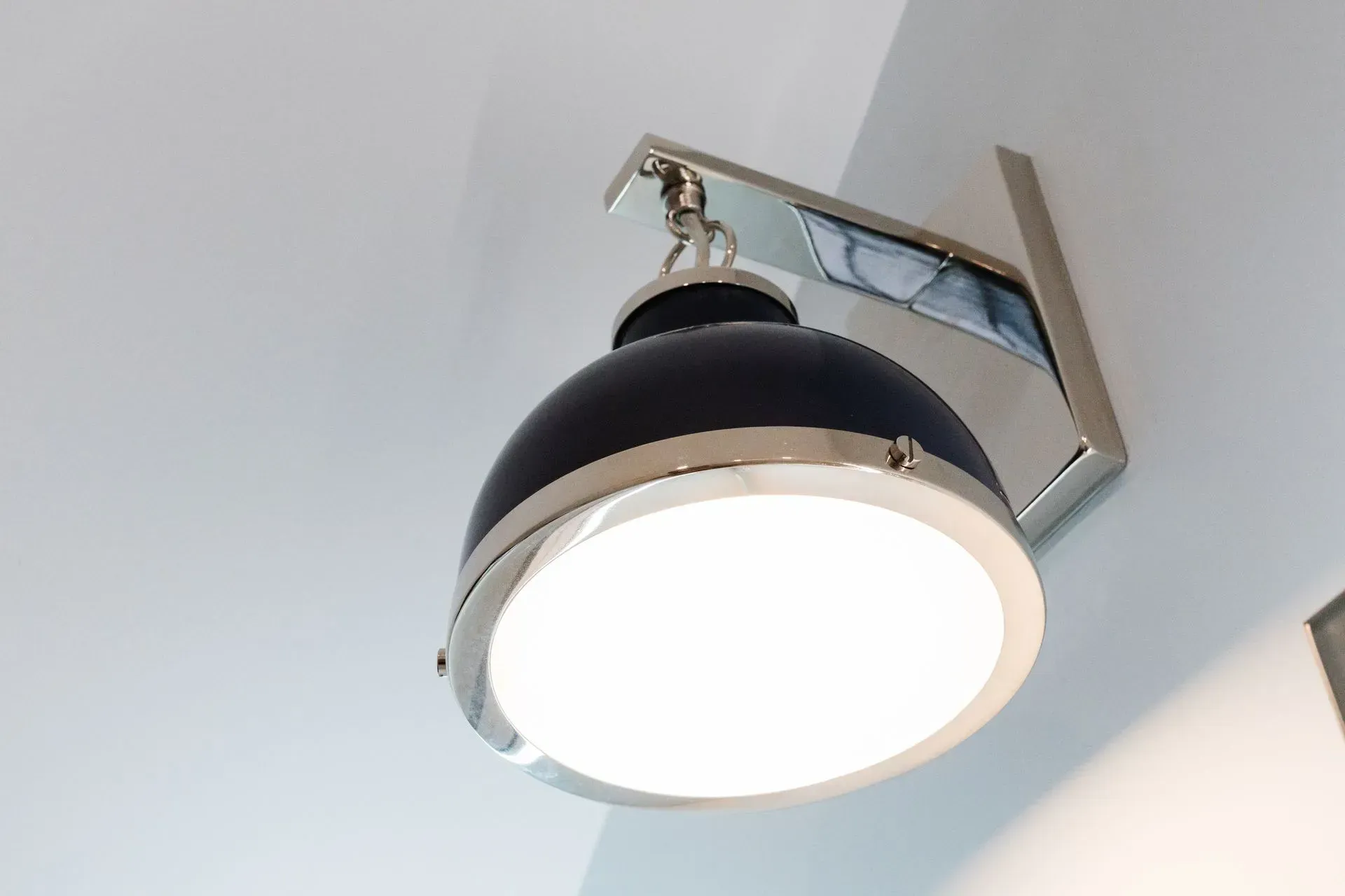 Black ceiling pendant light with a frosted glass shade against a white ceiling