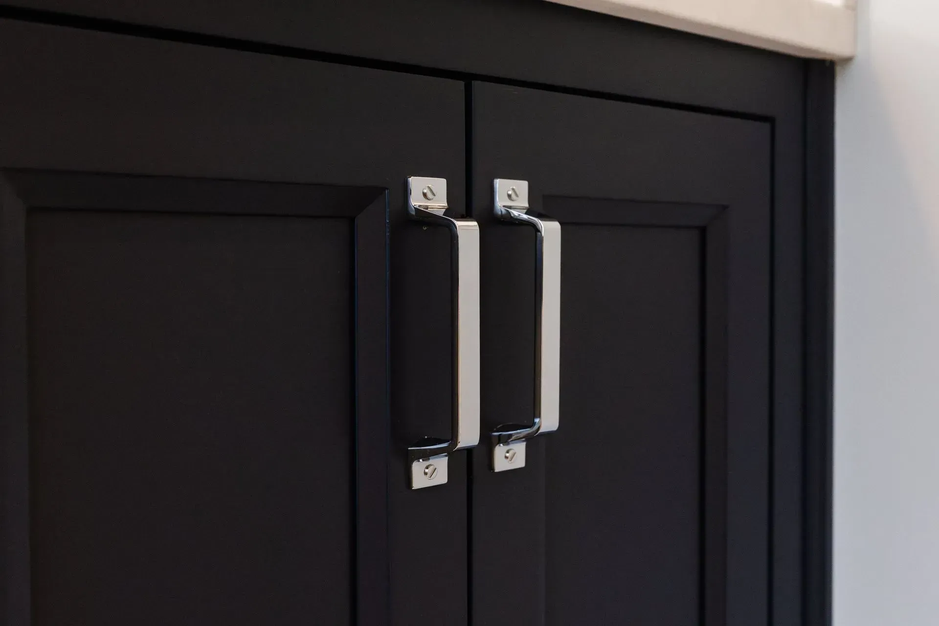 Black cabinet doors with silver handles and silver corner accents