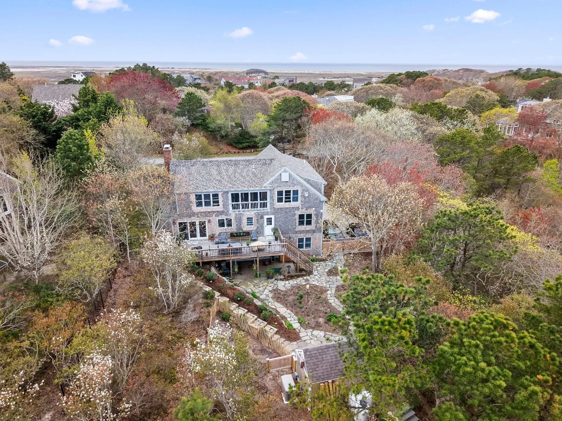 Large white house amid autumn trees, viewed from above under a blue sky.