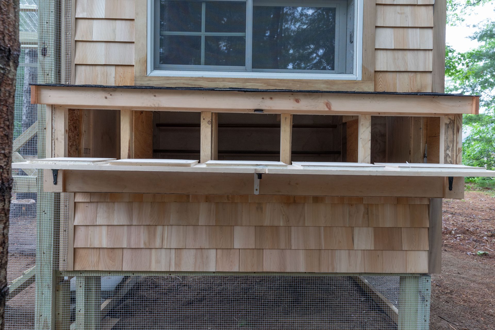 Partially built porch with exposed framing and a window above, on a wooden house exterior