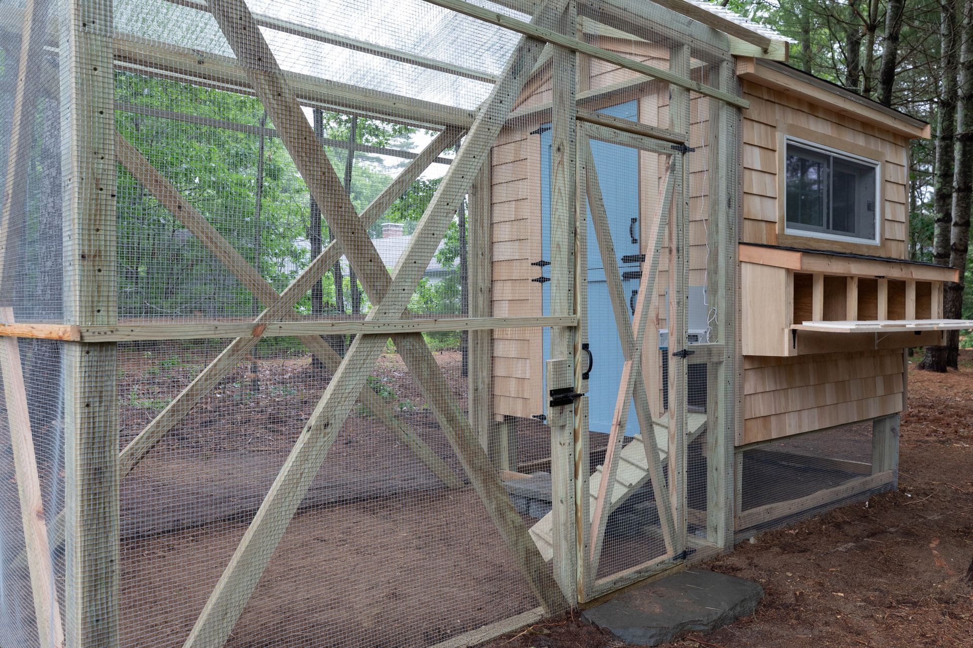 Outdoor chicken coop with wire mesh, wooden frame, and a small enclosed nesting box
