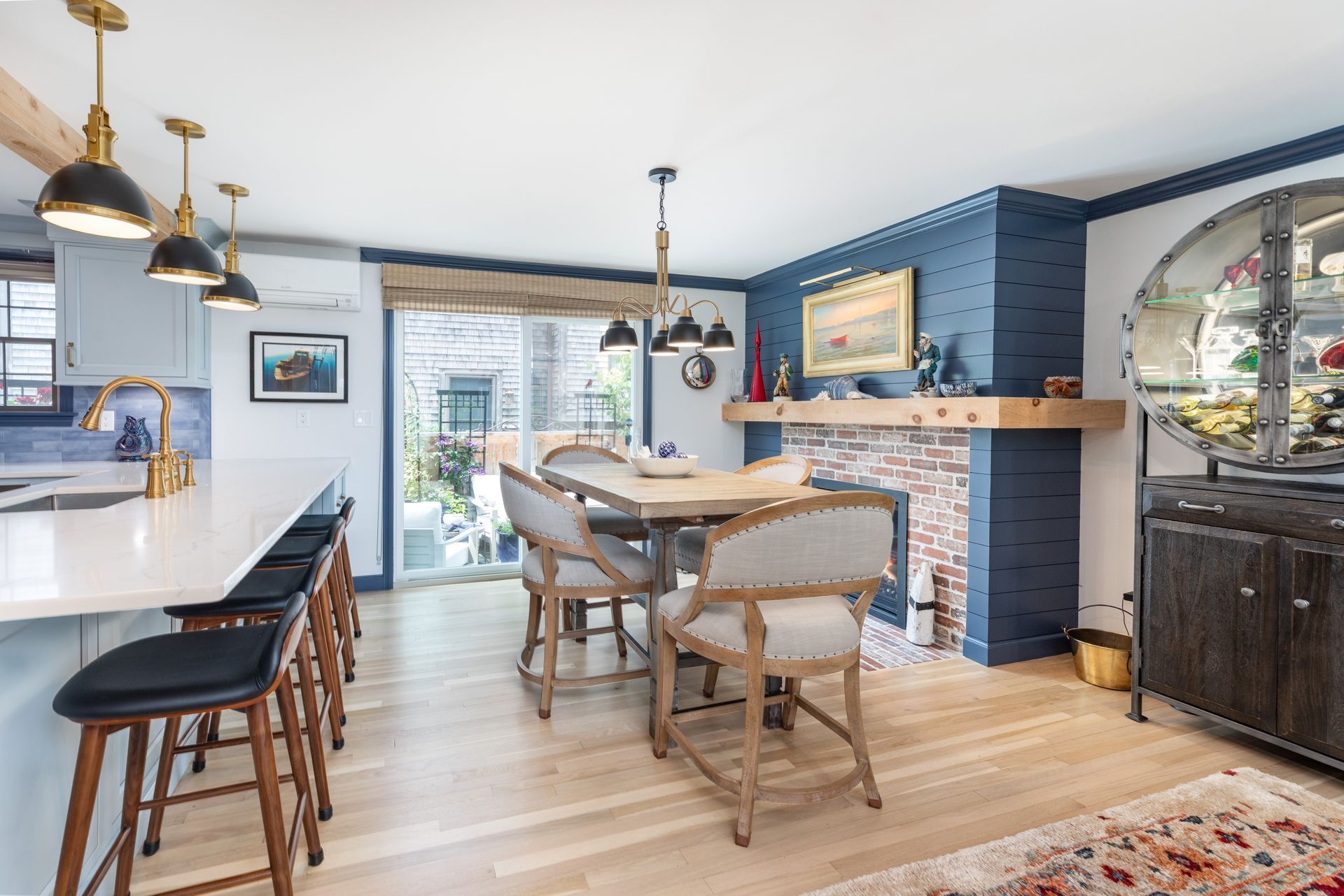Bright dining room with blue walls, white island, wooden table, and sliding glass doors to a deck