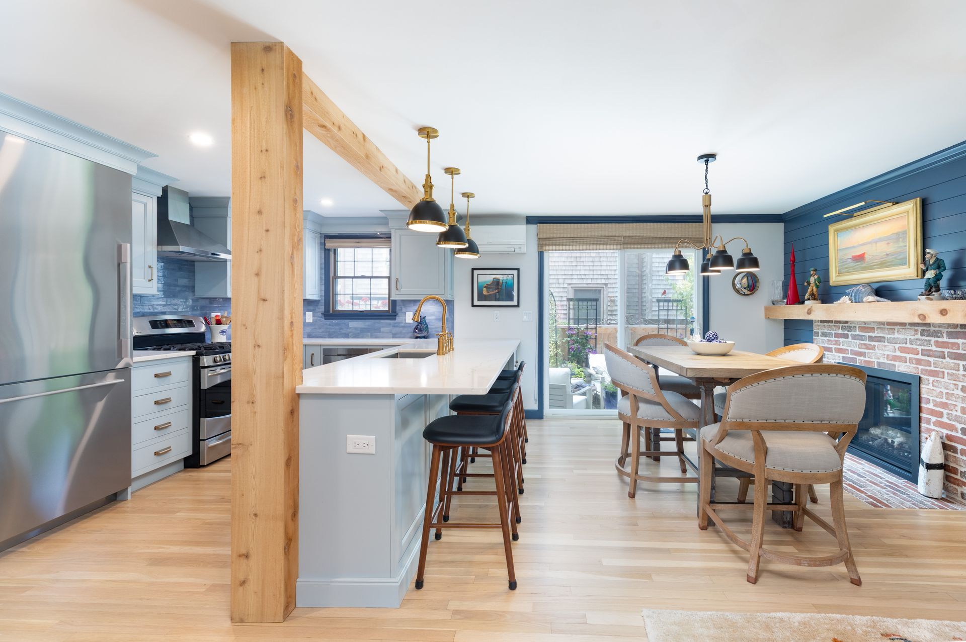 Bright open kitchen and dining area with blue walls, wood floors, and barstools by a large island.