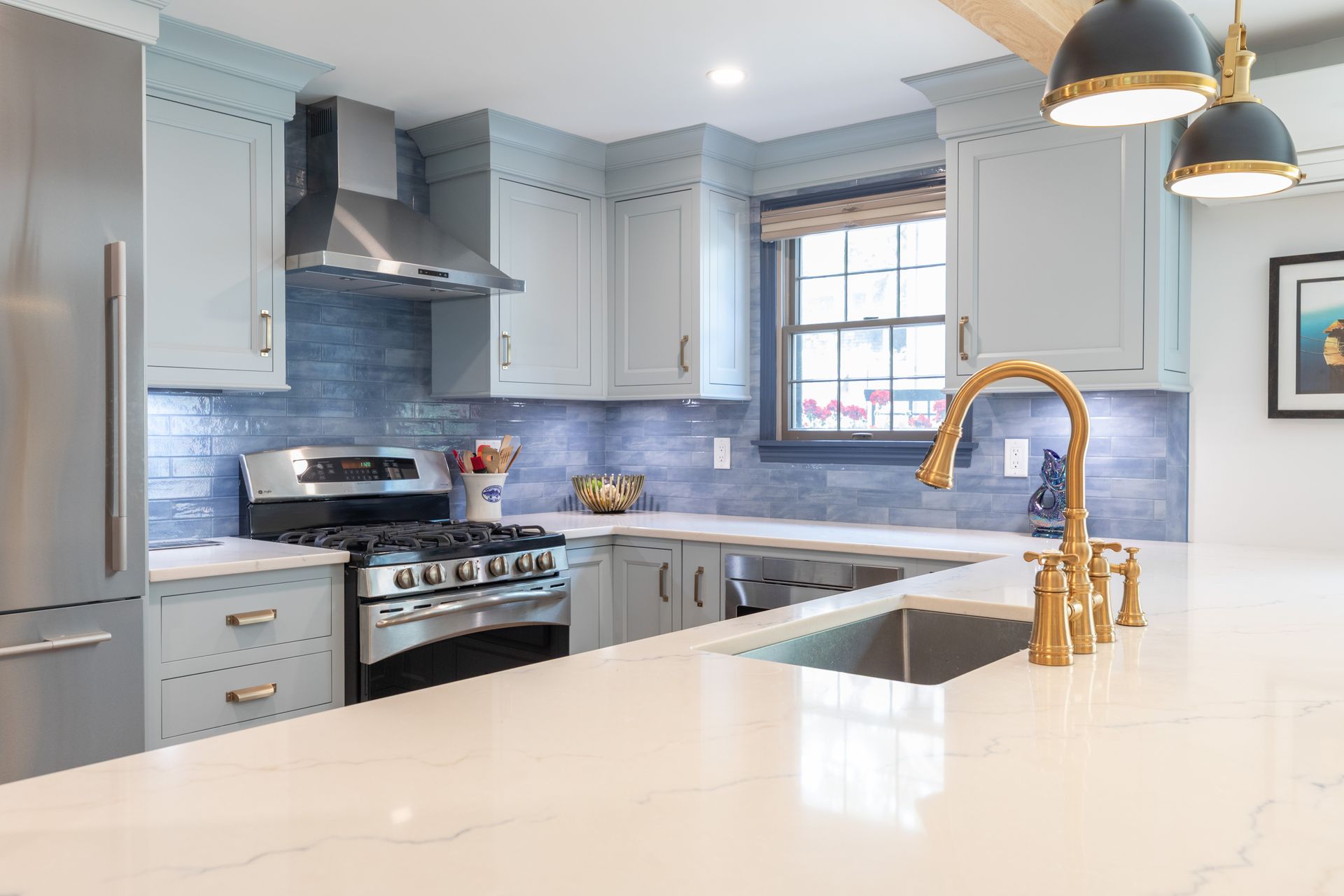 Bright modern kitchen with blue cabinets, stainless steel appliances, and a white island countertop