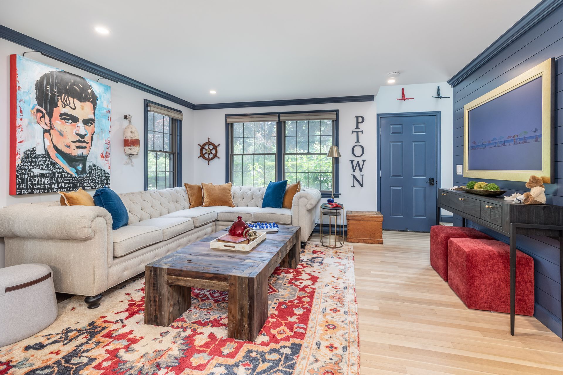 Bright living room with cream sectional, patterned rug, coffee table, blue door, and wall art