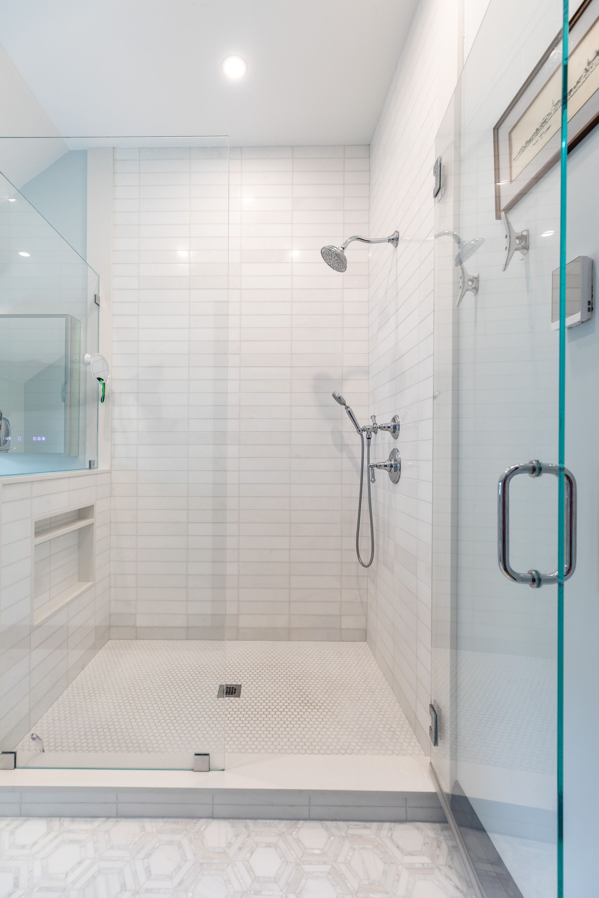 White tiled walk-in shower with glass door, rainfall showerhead, and built-in bench.
