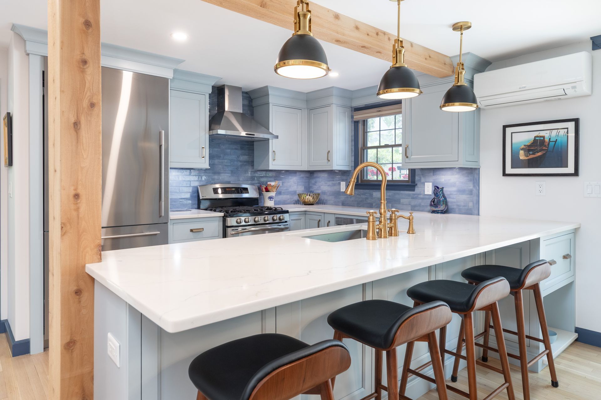 Modern kitchen with white island, black barstools, pendant lights, and light blue cabinets