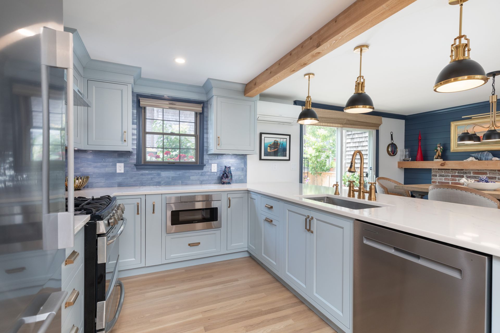 Bright blue kitchen with white counters, wood floors, pendant lights, and a window over the sink.