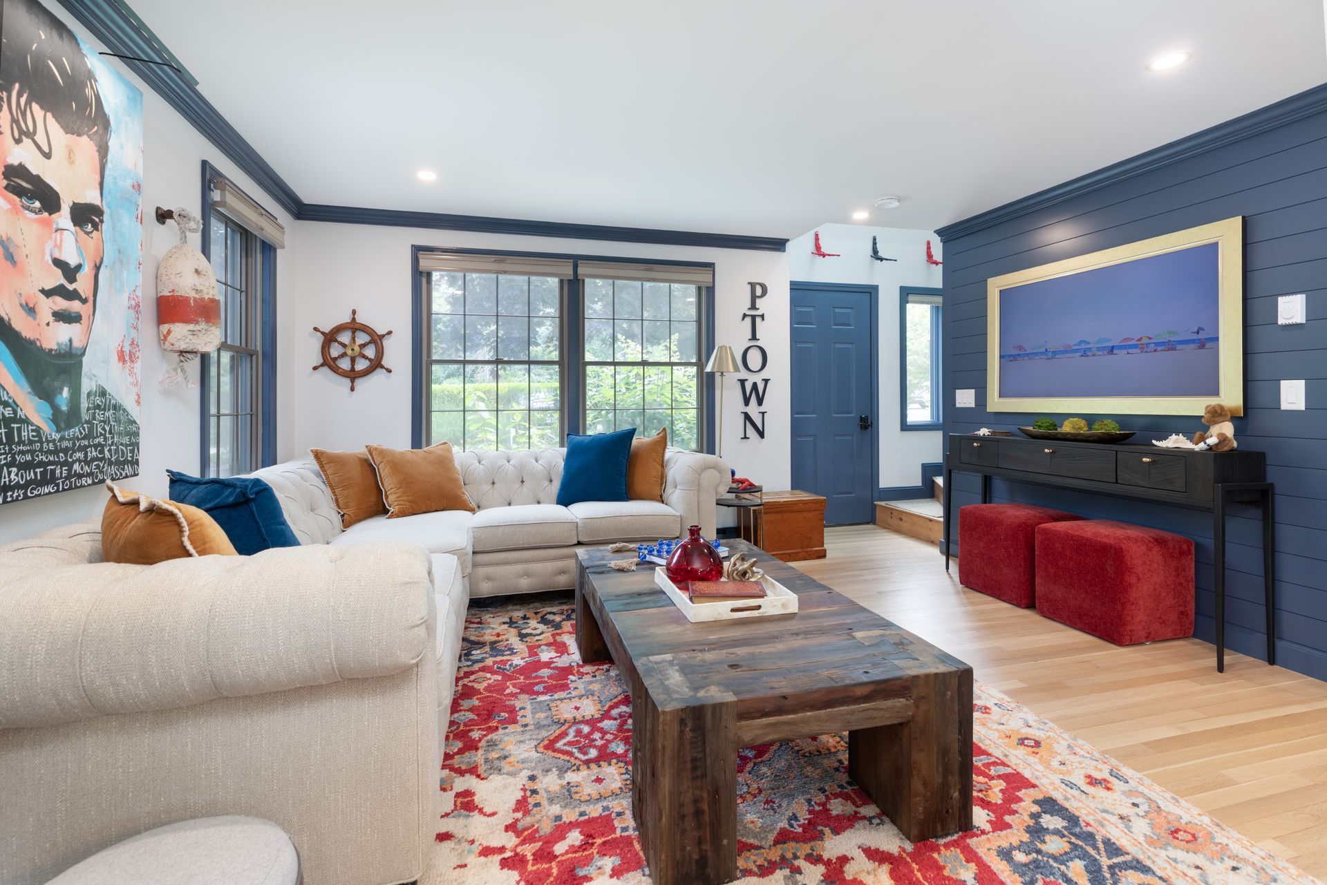 Bright living room with white sectional, blue walls, red rug, coffee table, and large wall art