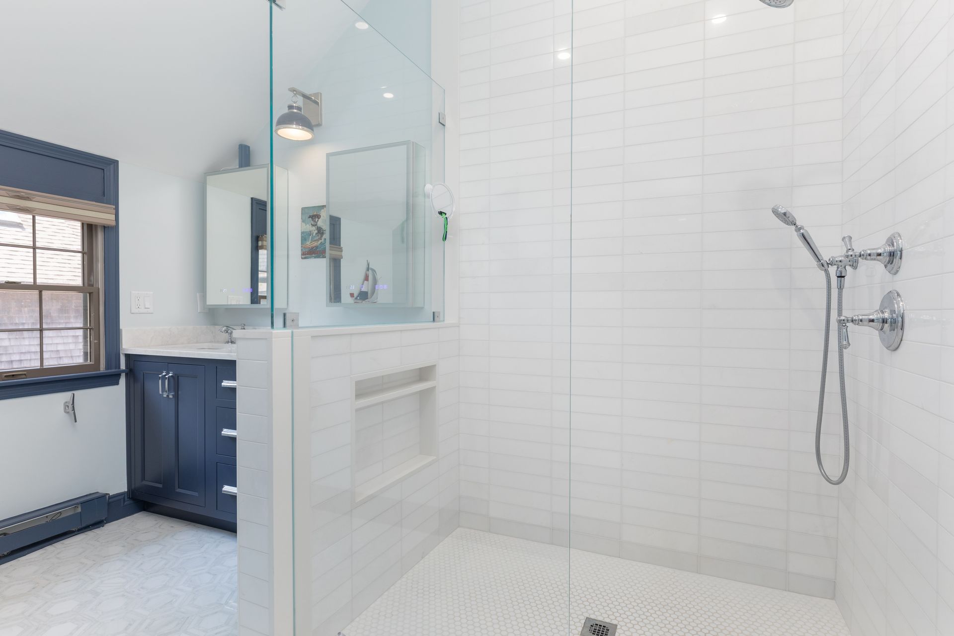 Modern bathroom with white tiled shower, glass enclosure, and blue vanity cabinetry