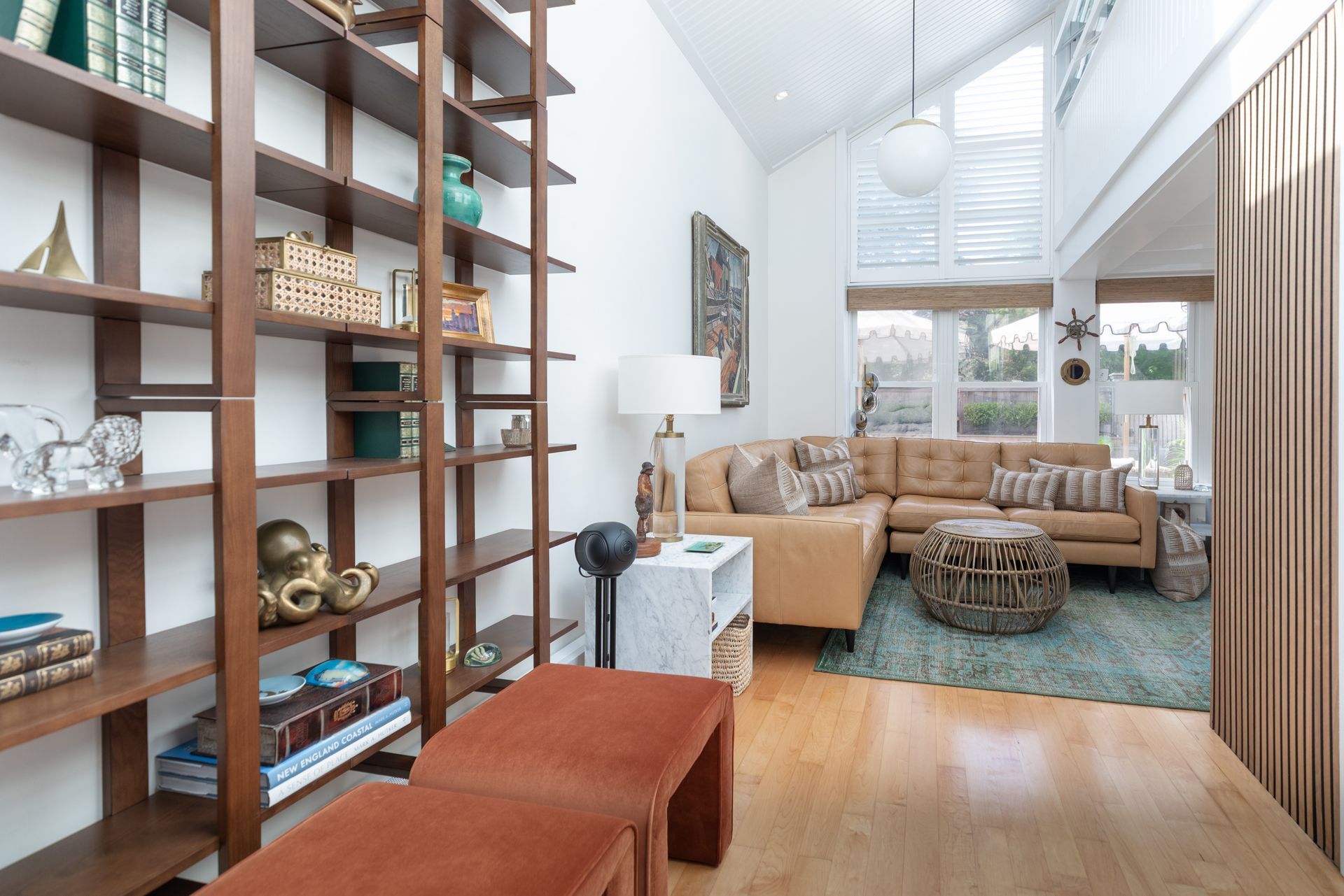 Modern living room with tan sectional, turquoise rug, and open shelving beside a staircase