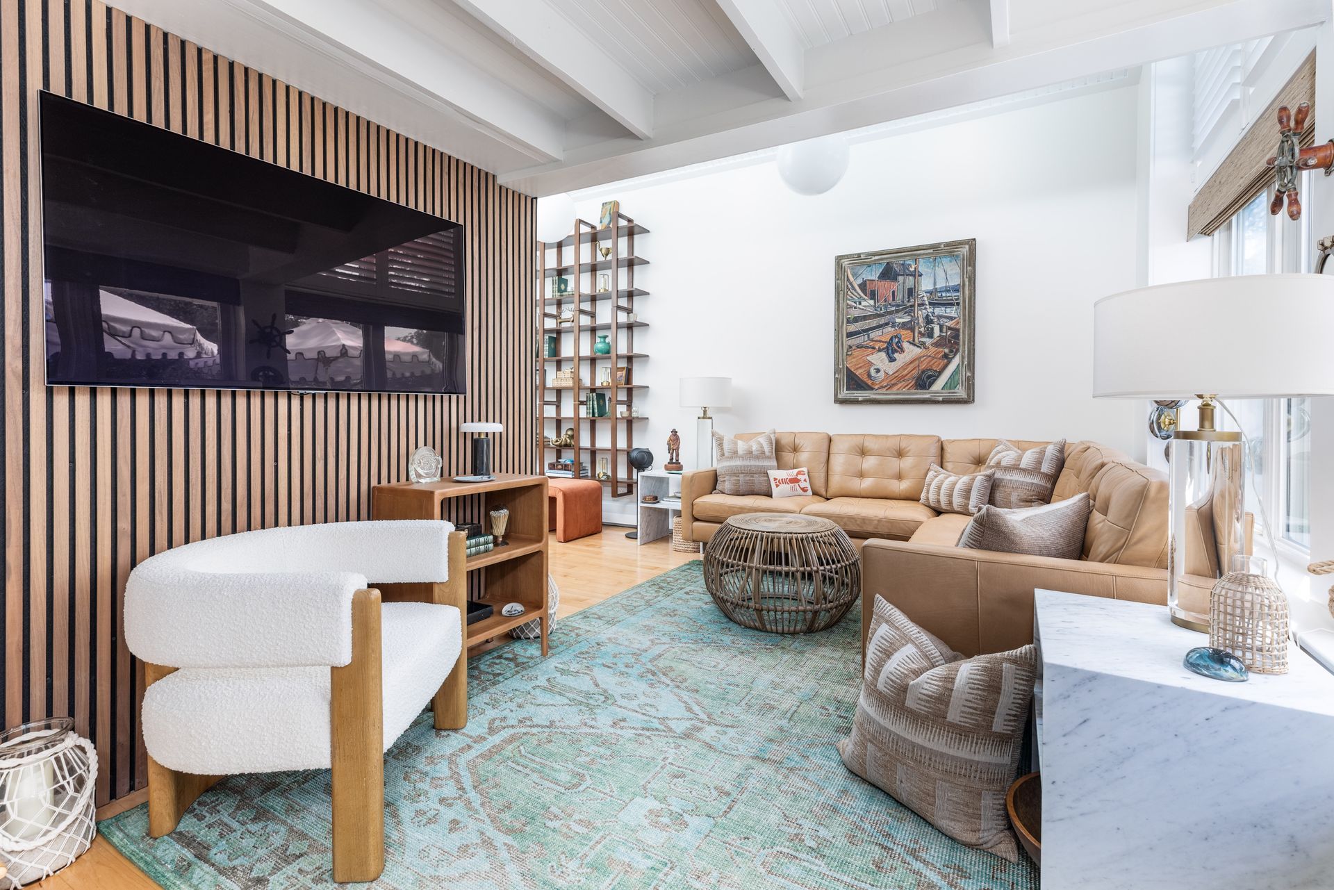 Bright living room with beige sofa, white armchair, large TV, patterned rug, and modern decor