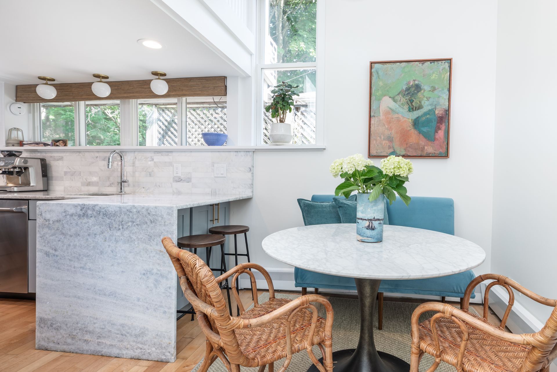 Cozy kitchen nook with round table, wicker chairs, and a bright marble island in the background