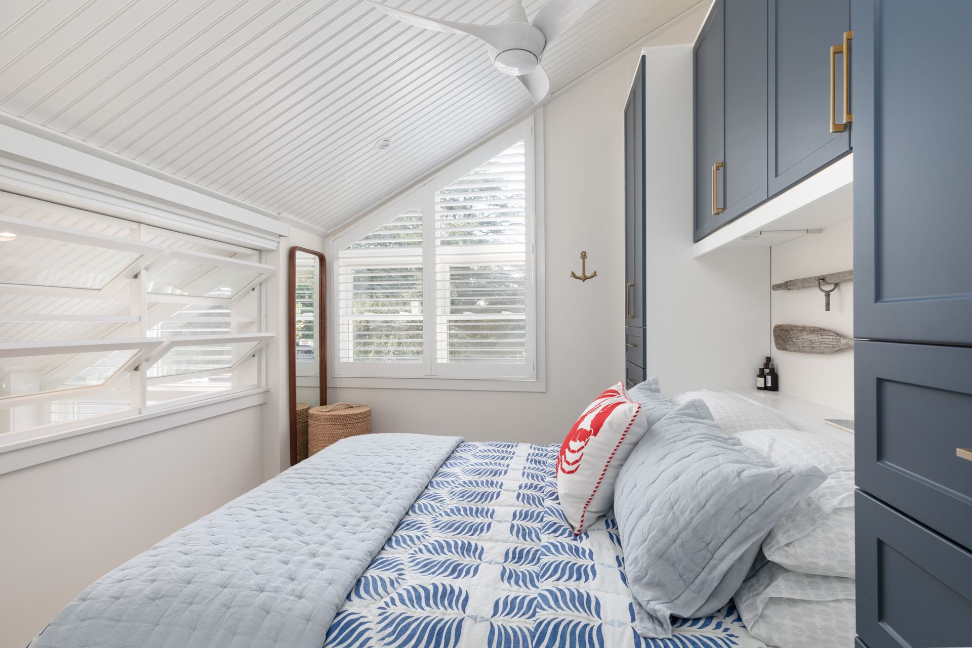 Bright bedroom with a blue bedspread, gray cabinets, and a window with white blinds