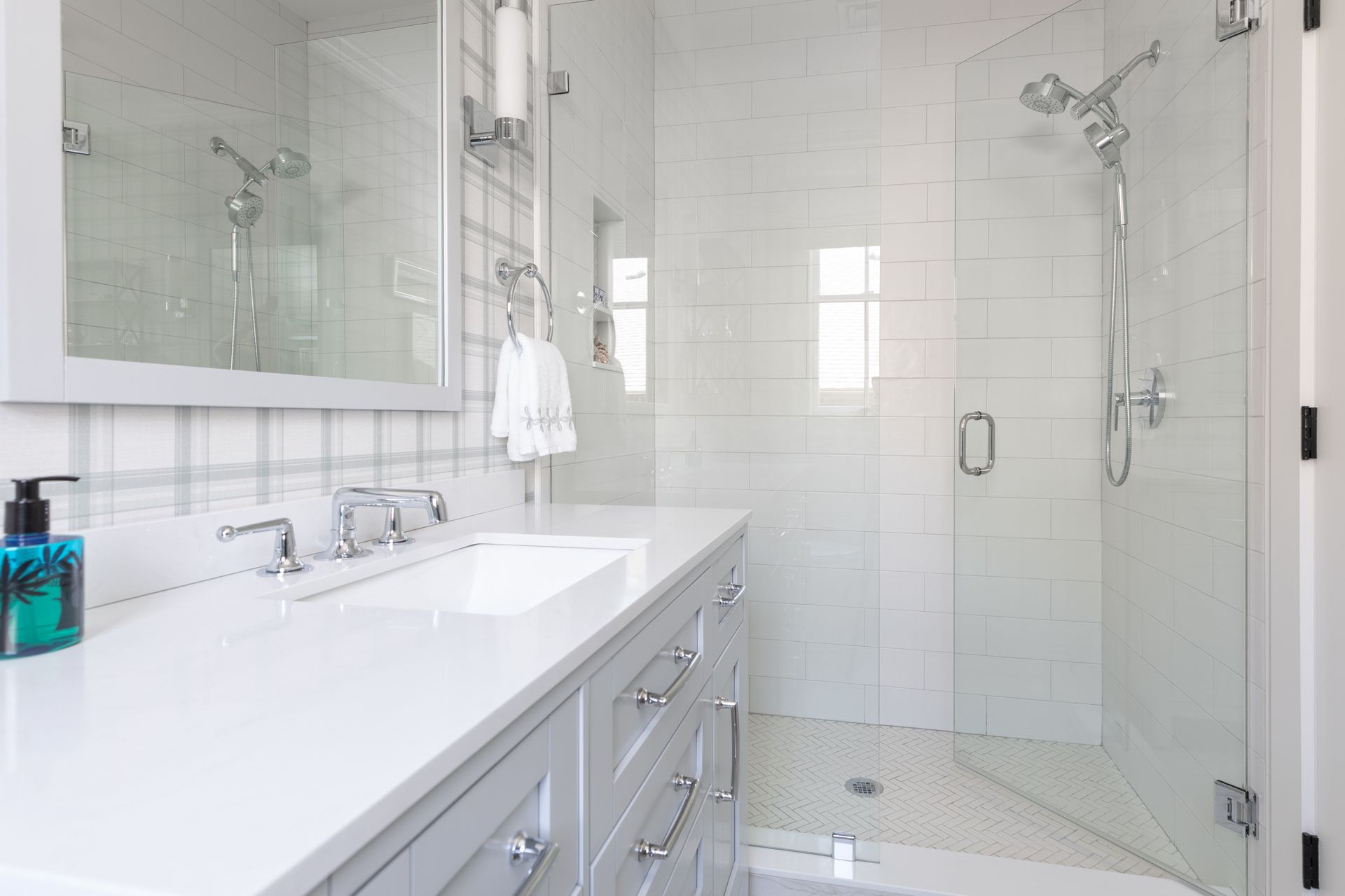 Bright white bathroom with double vanity, large mirror, and glass-enclosed shower