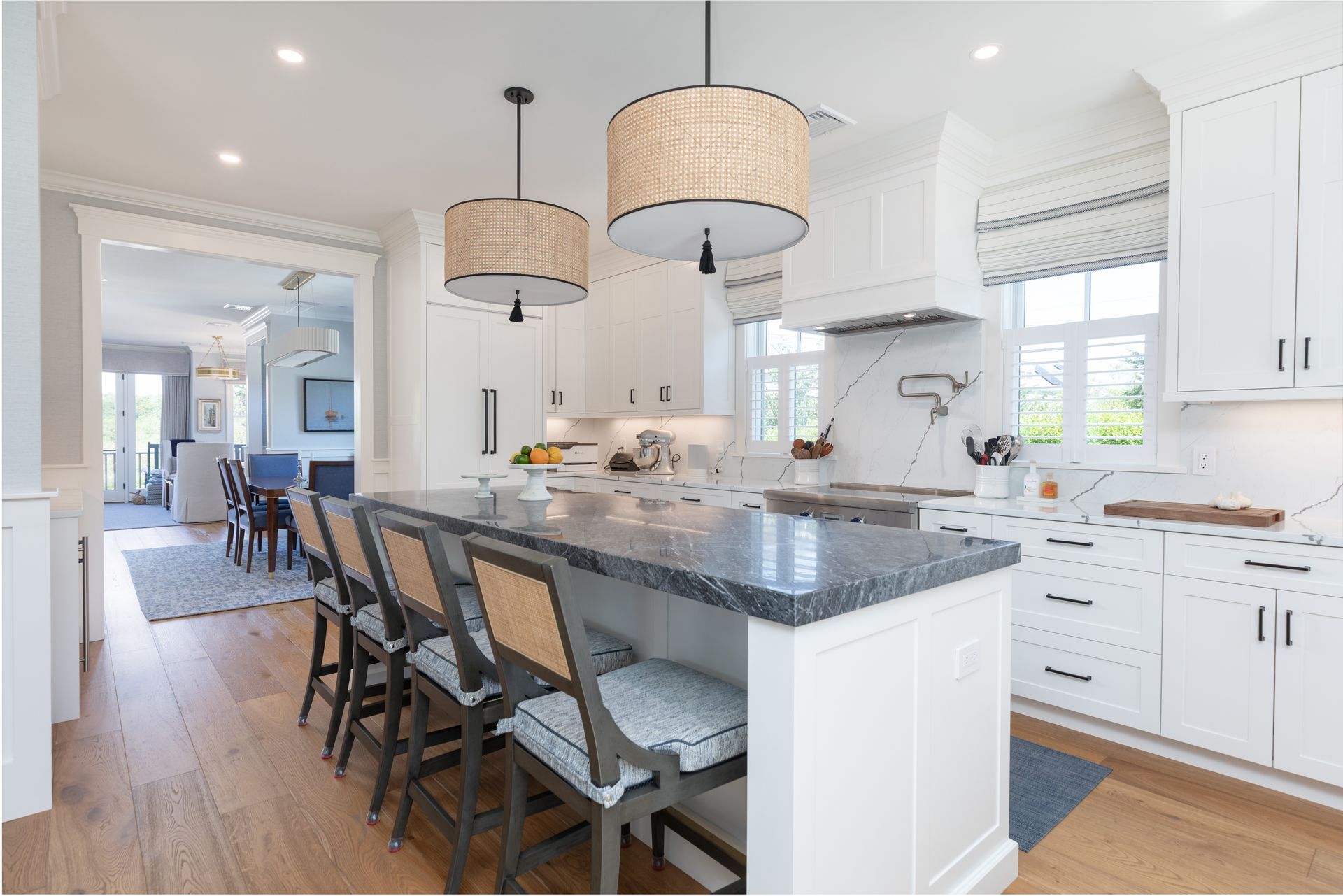Bright white kitchen with a dark island, bar stools, and pendant lights.