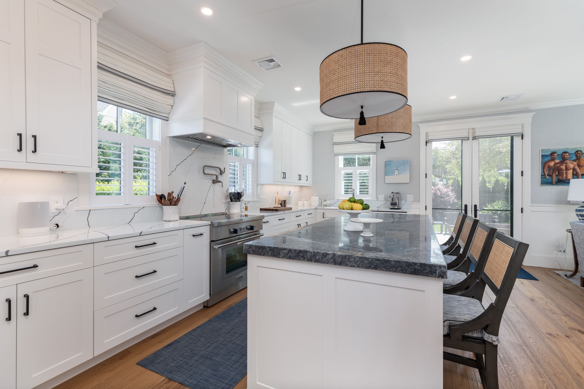 Bright white kitchen with a dark granite island, pendant lights, and a view into a dining area.