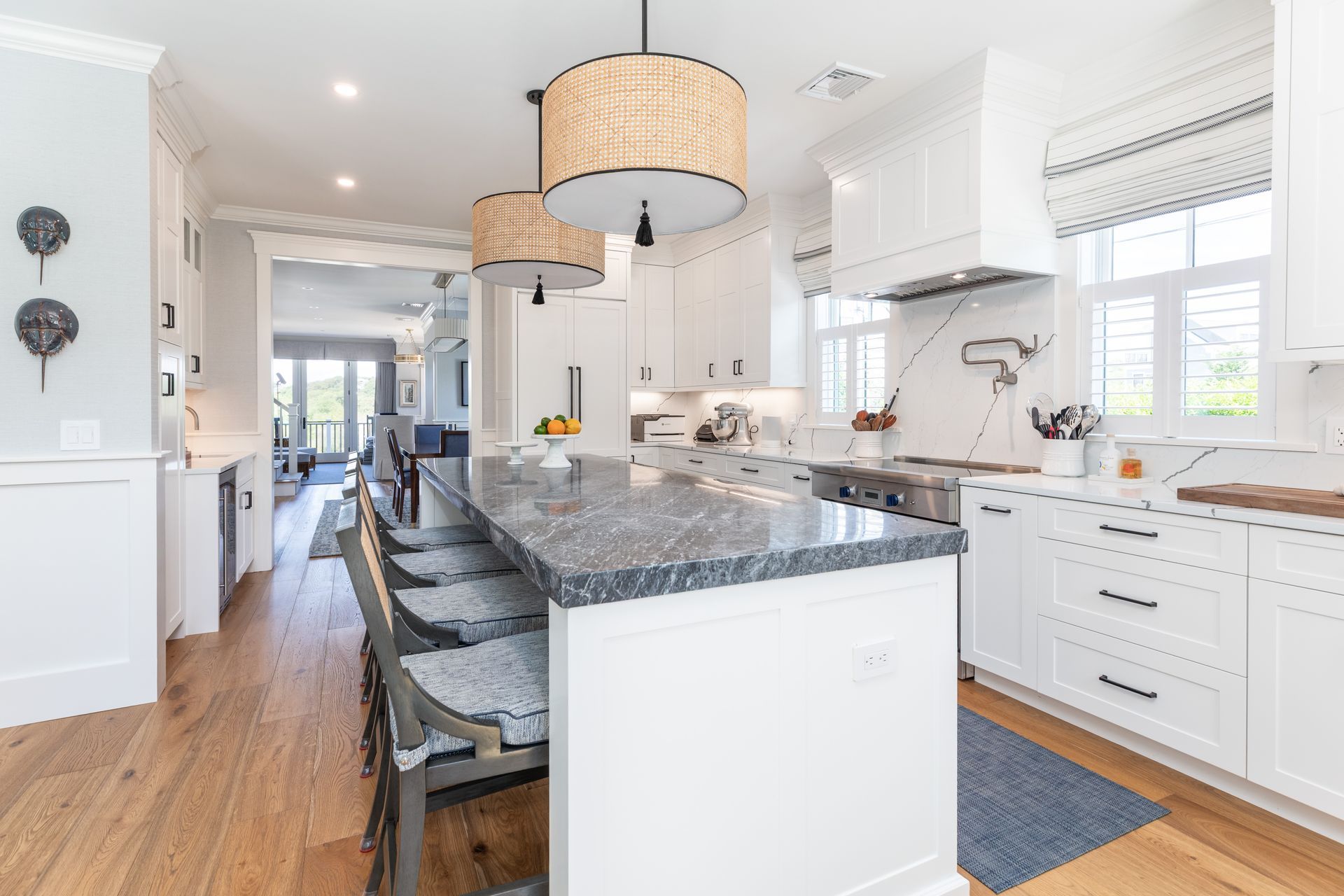 Bright white kitchen with granite island, pendant lights, and hardwood floors