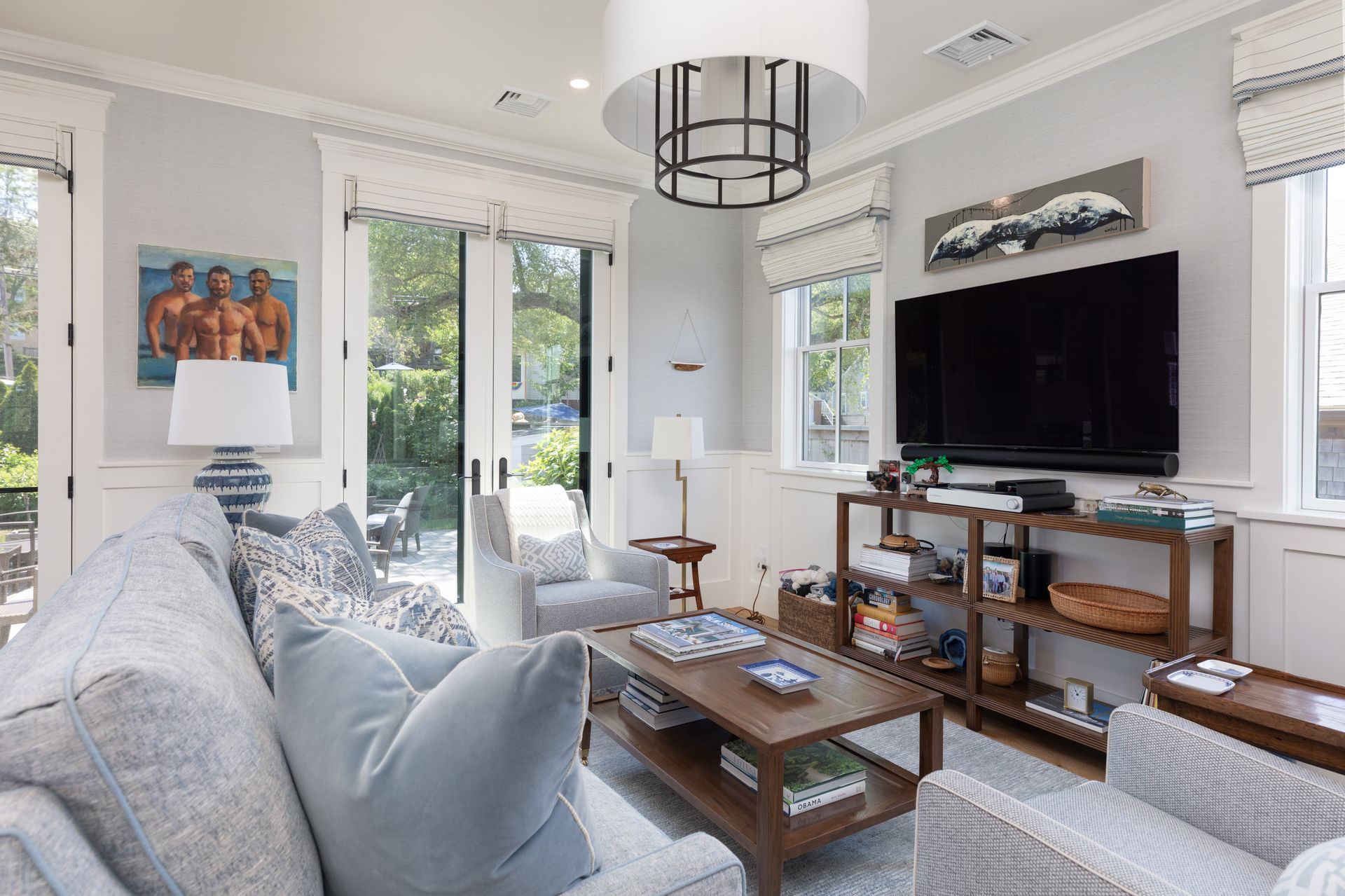 Bright living room with gray sofa, wall-mounted TV, coffee table, and sliding doors to greenery