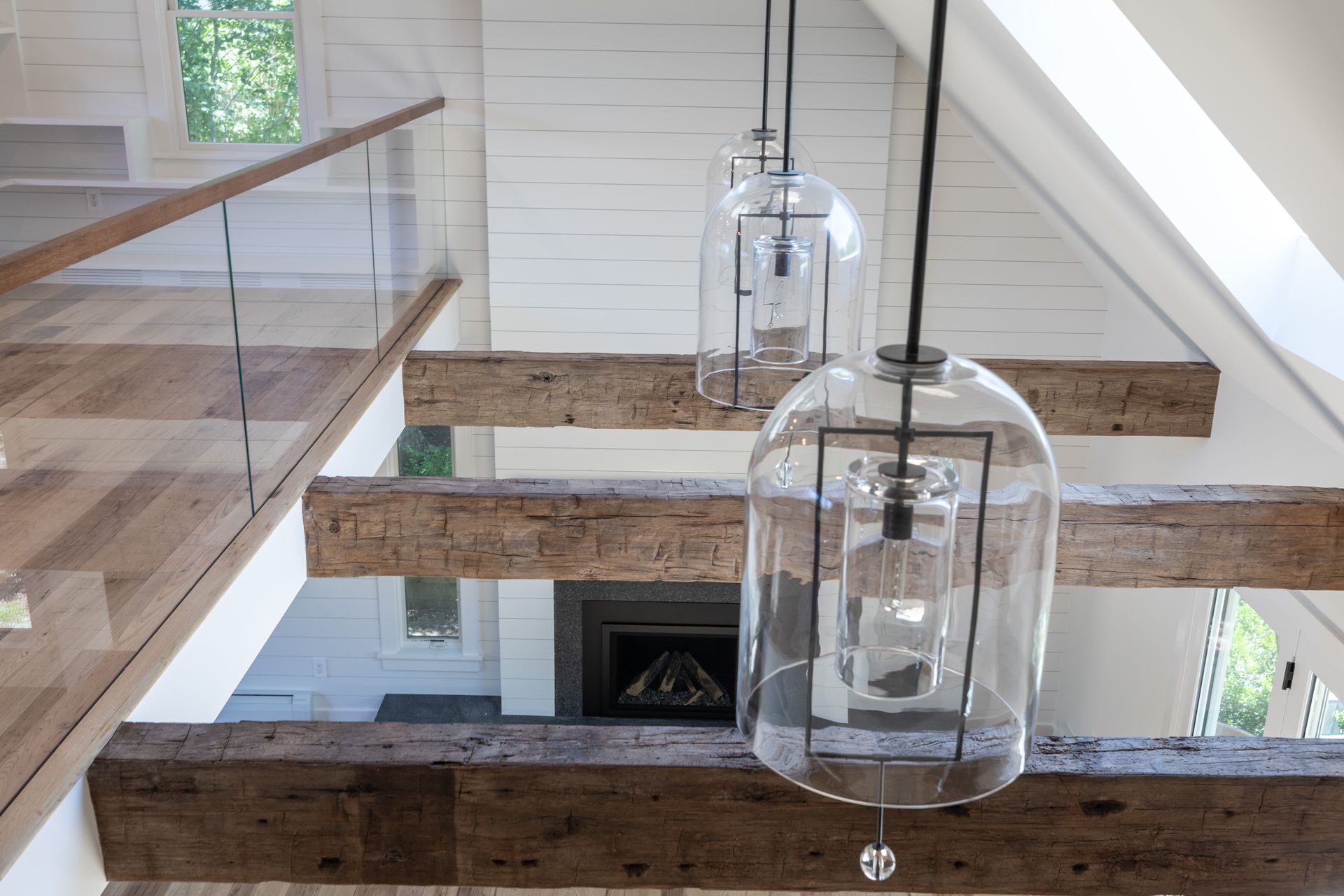 Modern staircase with glass pendant lights and a fireplace visible below