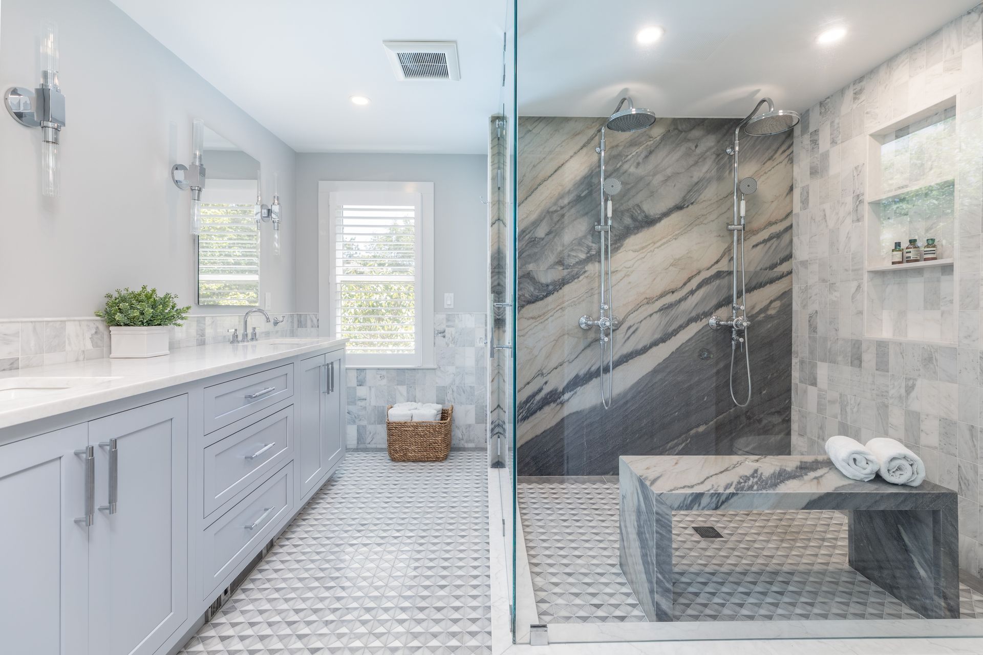 Bright modern bathroom with double vanity, glass shower, and marble tile accents