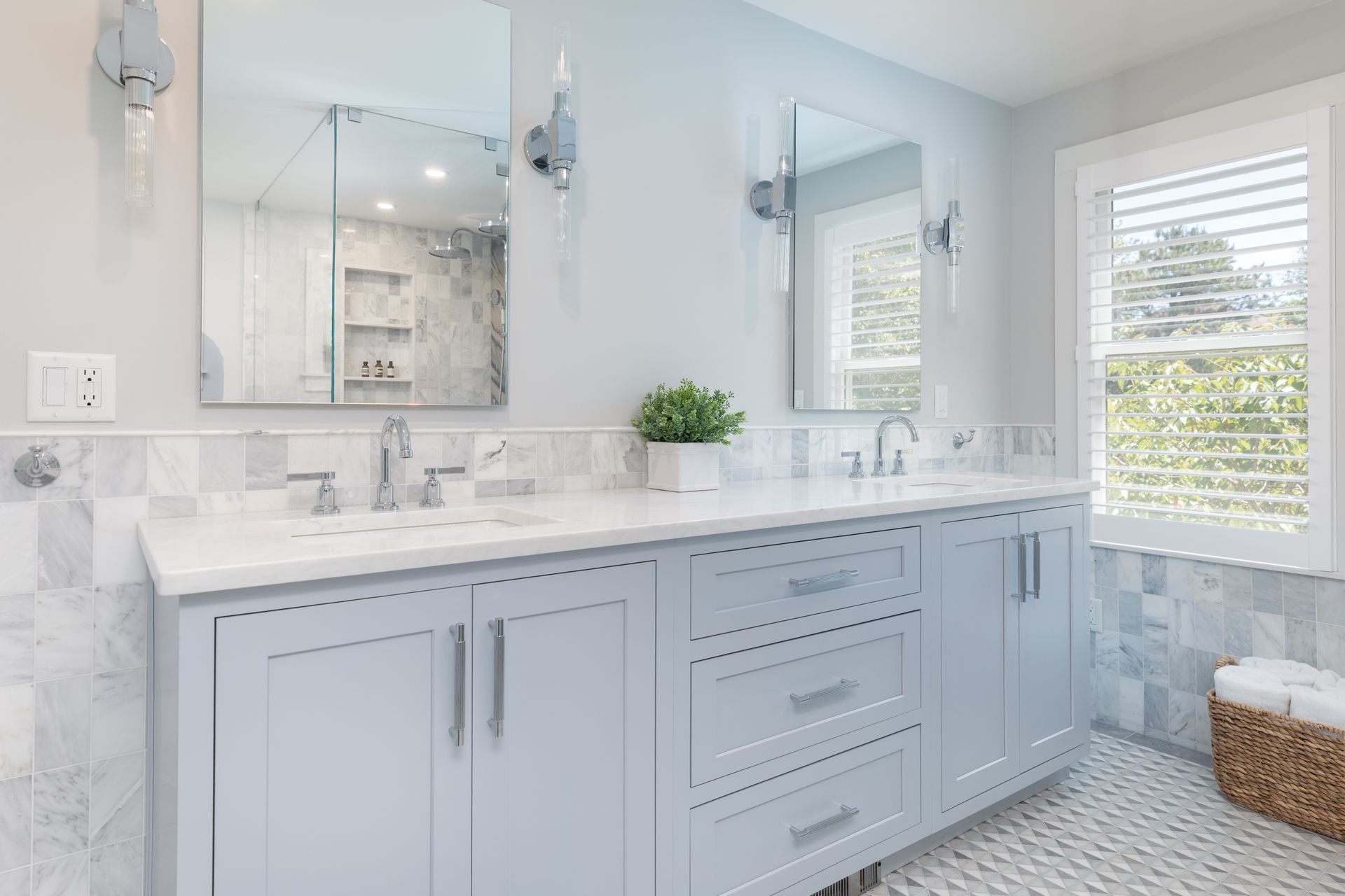 Bright bathroom with light blue double vanity, white countertop, mirrors, and window blinds.
