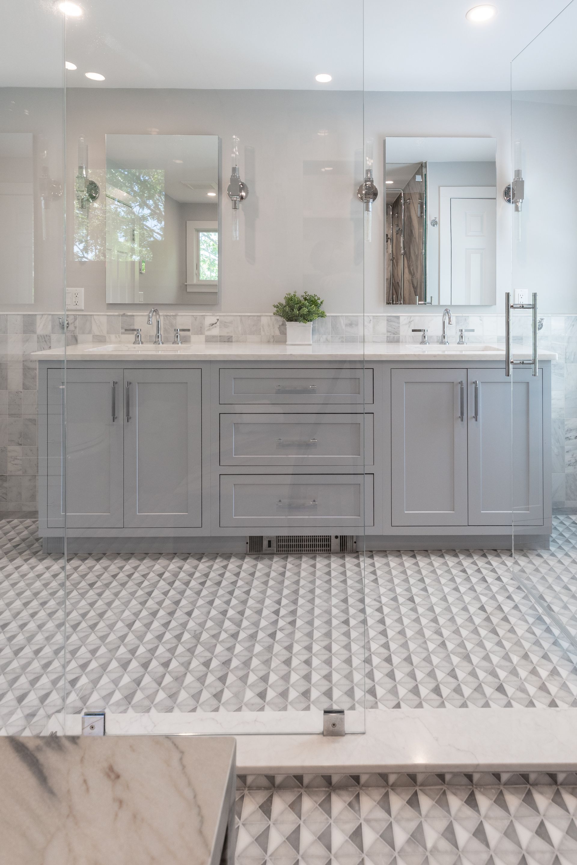 Bright white bathroom vanity with double sinks, large mirrors, and patterned tile floor