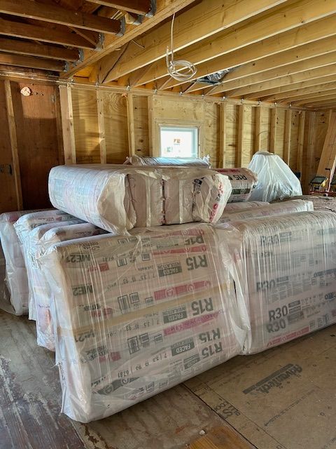 Stacks of insulation batts in a room under construction, labeled R15 and R30.