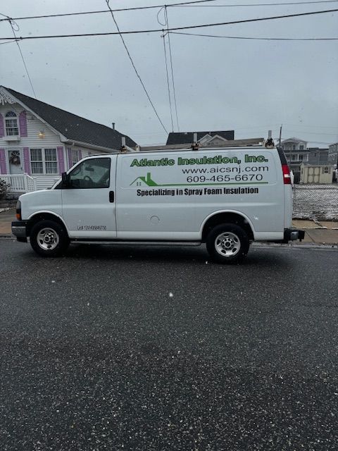 White Atlantic Insulation van parked on a wet road in front of a house.