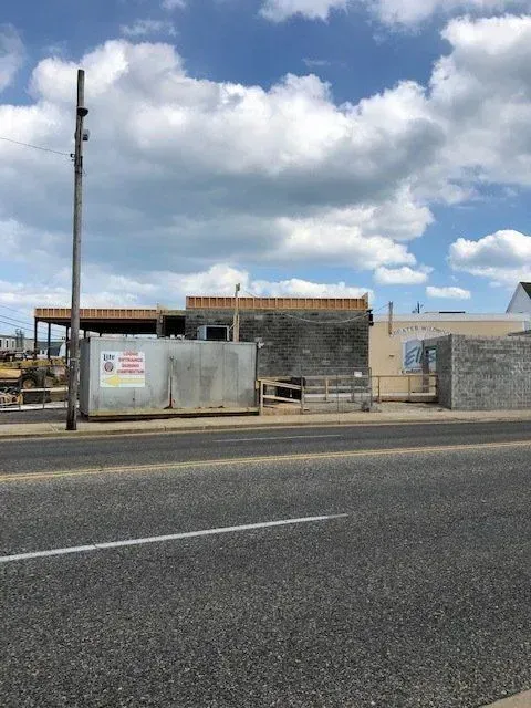 Construction site with a concrete block building under development against a partly cloudy sky.