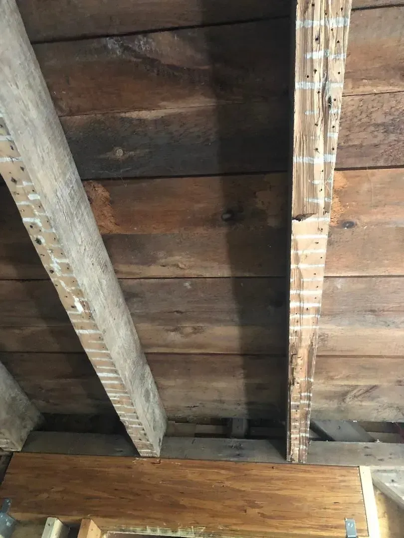 Wooden ceiling with exposed beams. The planks are dark brown.
