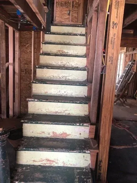 Staircase with worn, peeling paint, likely during construction or renovation of a building's interior.