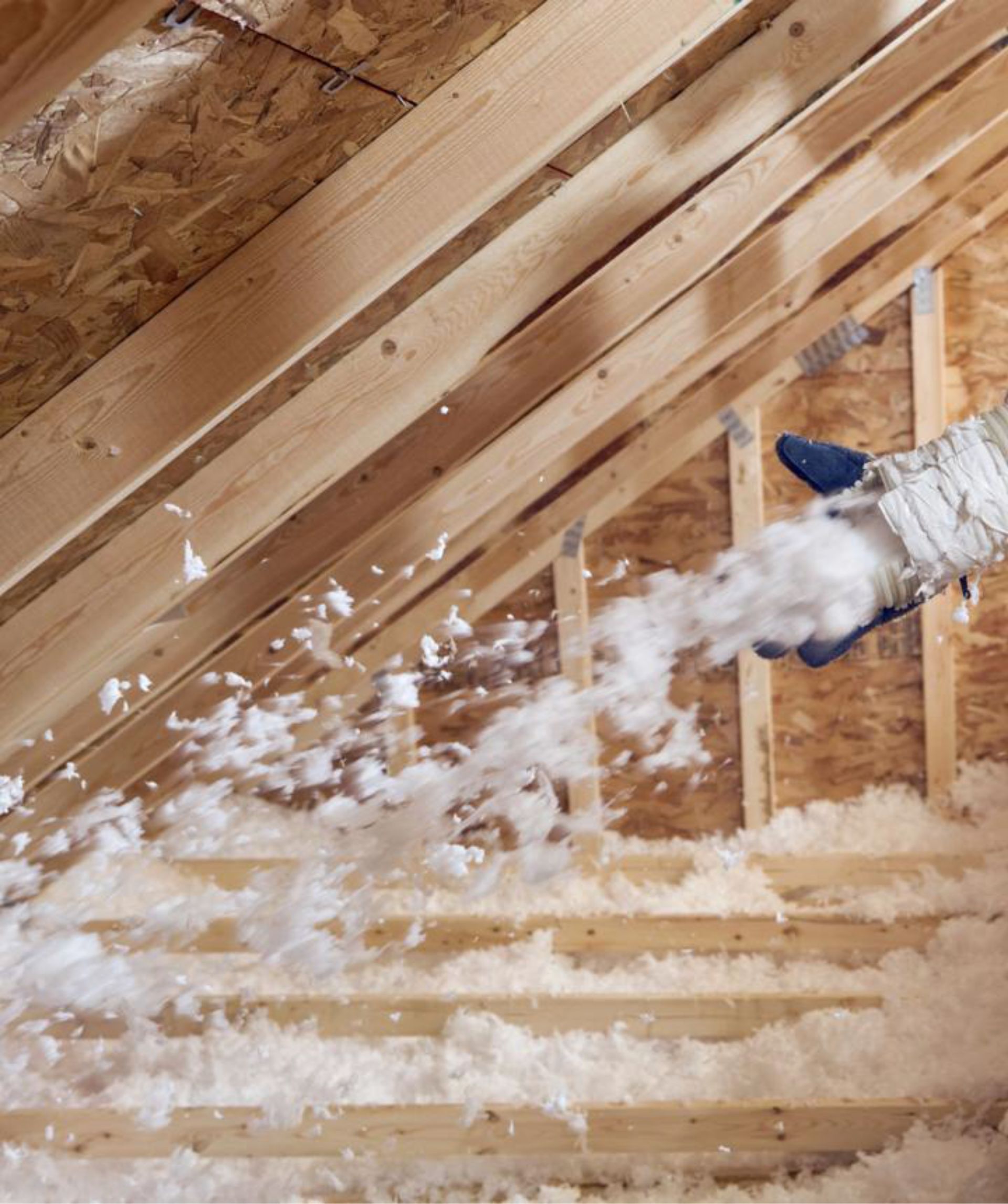 Insulated attic with exposed rafters as foam insulation is sprayed onto the walls and ceiling