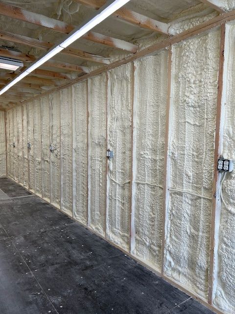 Spray foam insulated wall in an unfinished garage with exposed rafters and concrete floor