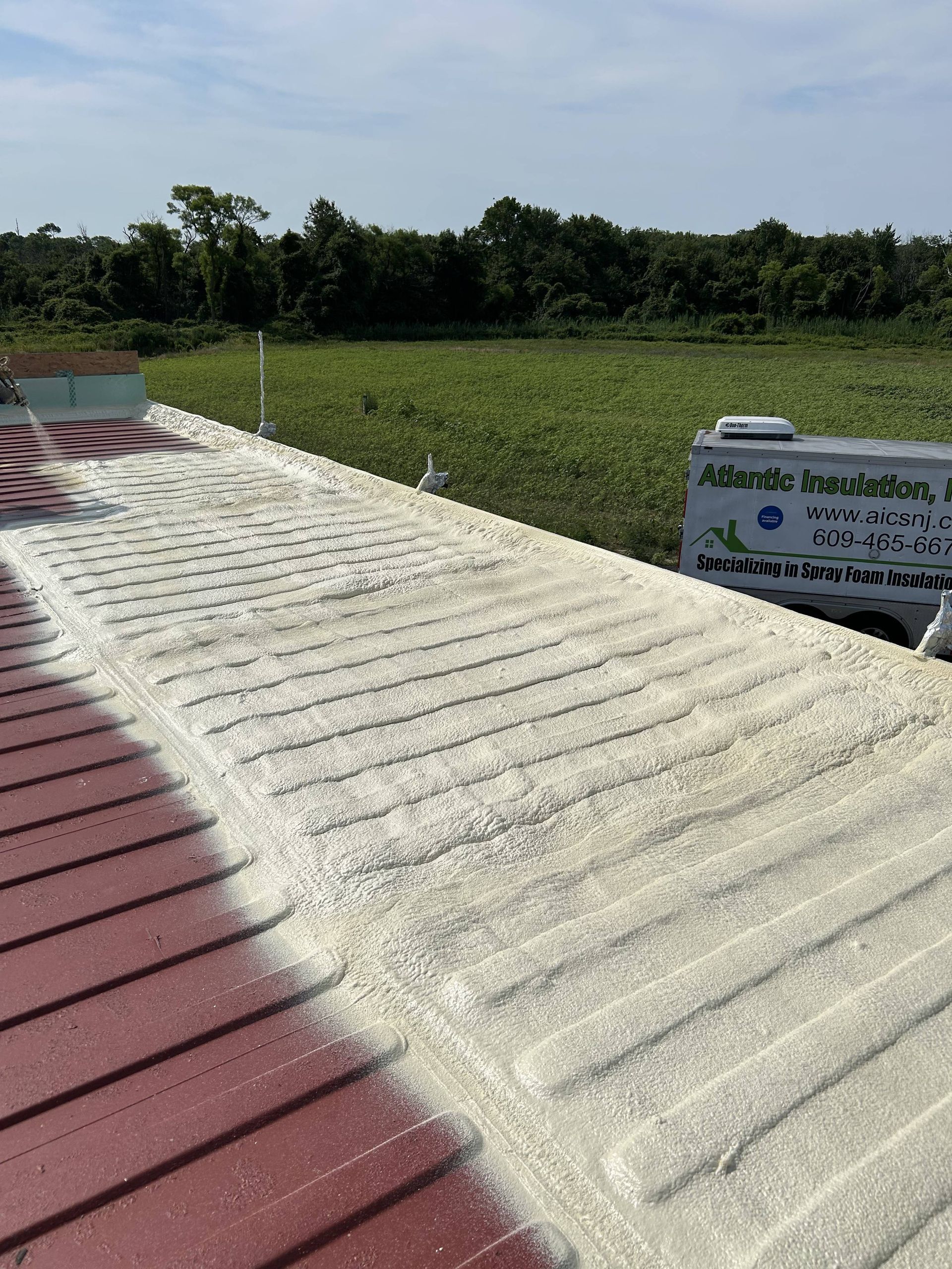 White rooftop with solar panels beside green fields under a clear sky