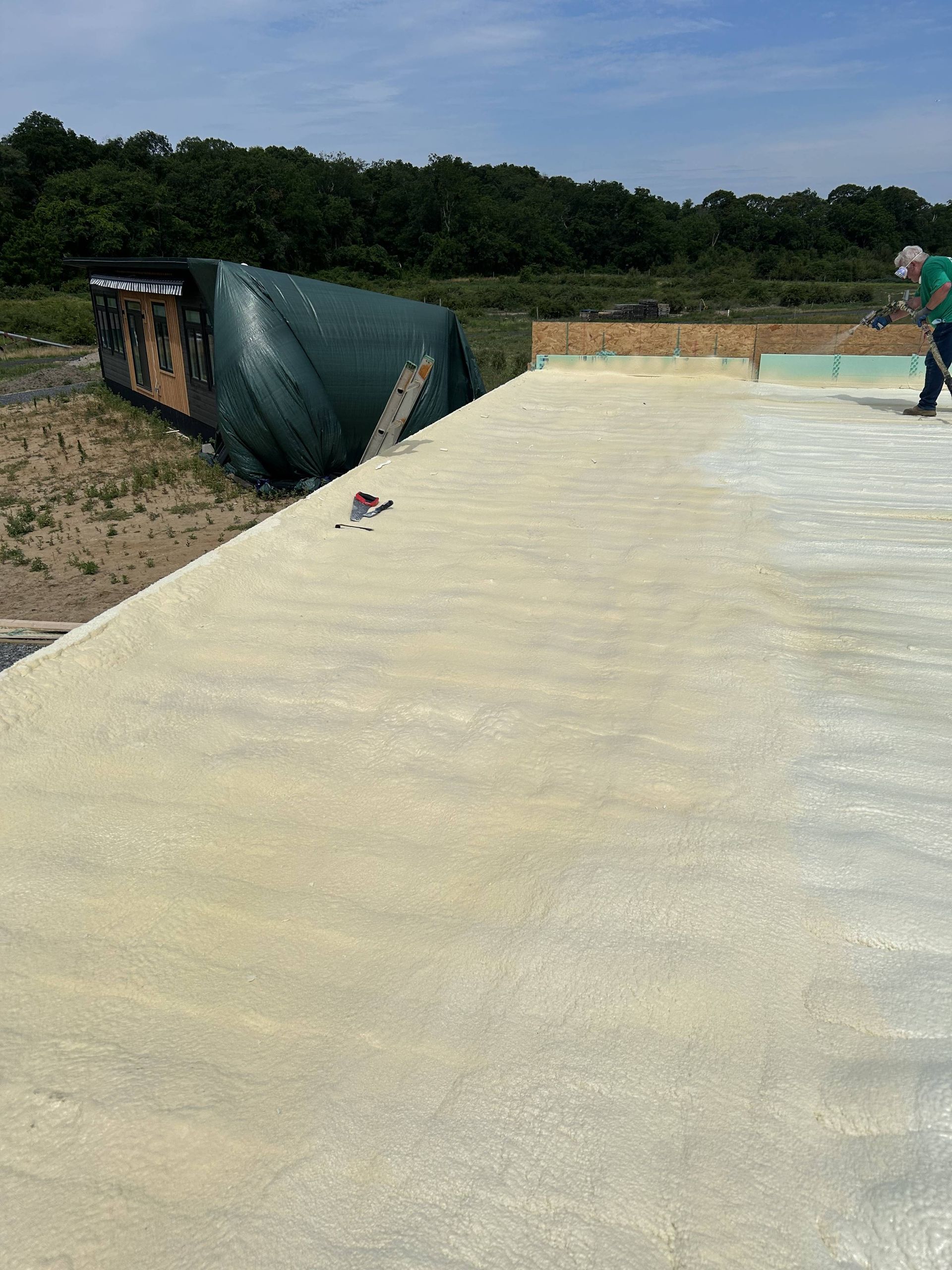 Concrete rooftop under construction with a worker on the right and trees in the background