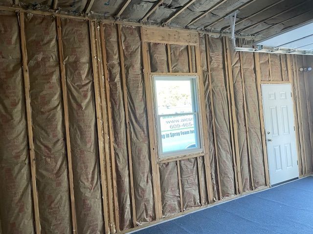 Interior wall framing with insulation, a window, and a door.