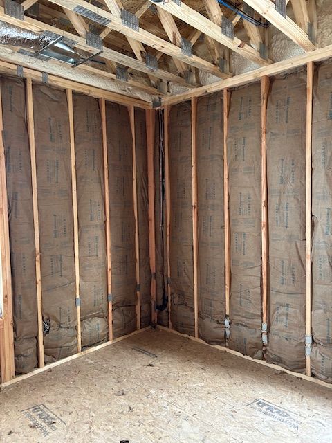 Interior of a room under construction, with insulated walls and wood framing.