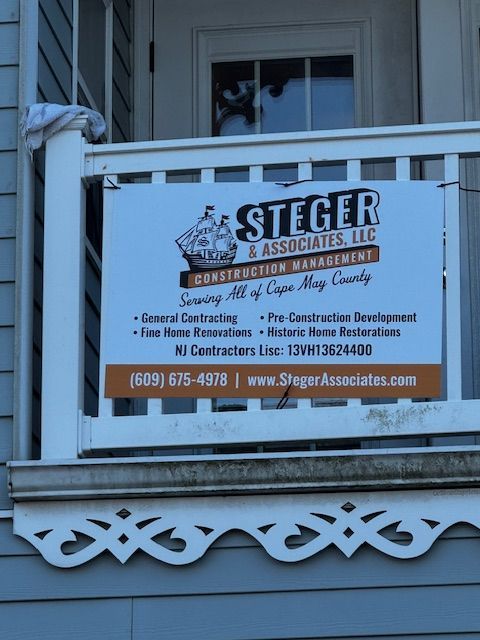 Sign for Steger & Associates LLC construction company on a porch railing; lists services and contact information.