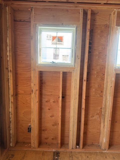 Wooden wall framing with a small window. Interior view of a construction site.