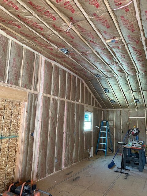Interior view of a building under construction, walls and ceiling insulated with pink fiberglass.
