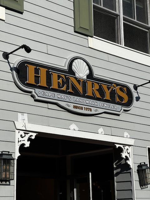 Henry's Cafe sign on a gray building. Black and gold lettering; seashell graphic. 'Since 1978' is below.