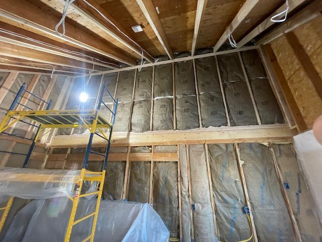 Exposed attic framing with insulation, ladder, and scaffold under construction