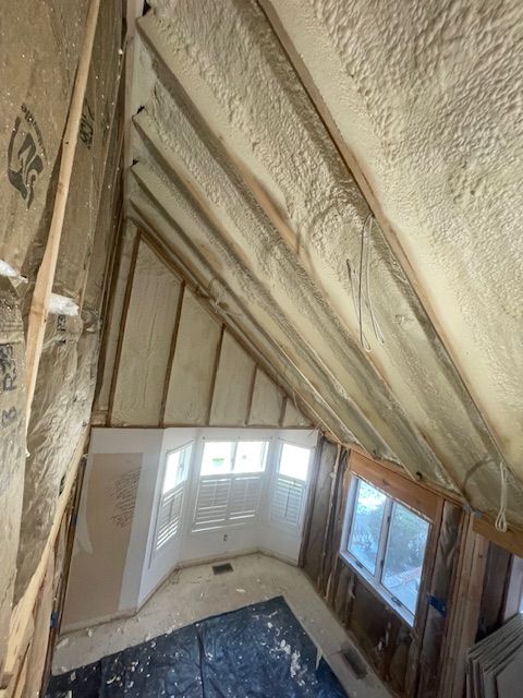 Interior of a room with a sloped, white insulated ceiling and large windows on one wall.