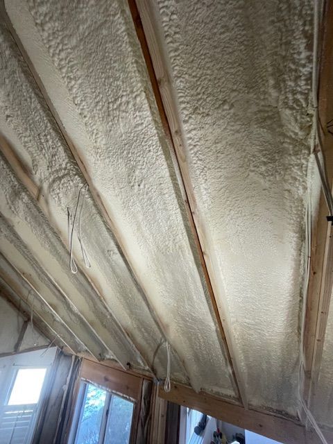 Open ceiling insulation with exposed rafters above a room window
