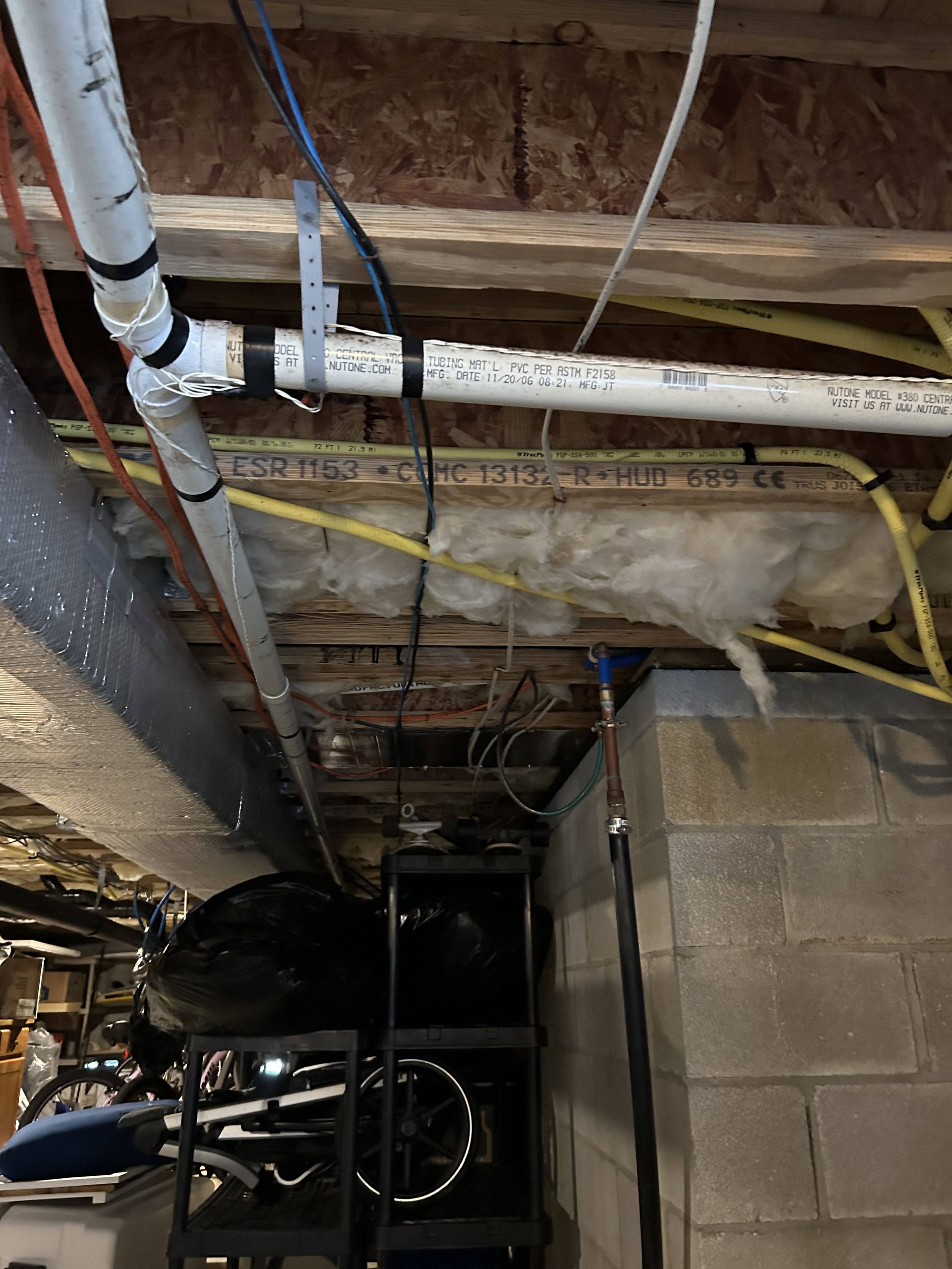Basement ceiling with exposed pipes, wiring, and ducts above concrete block walls.